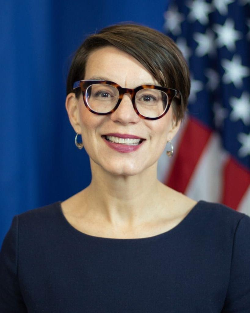 Woman smiling in front of American flag.