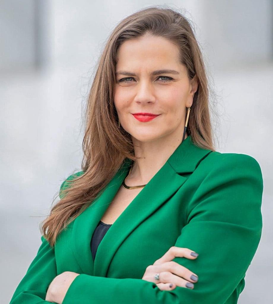 Professional woman in green blazer posing confidently.